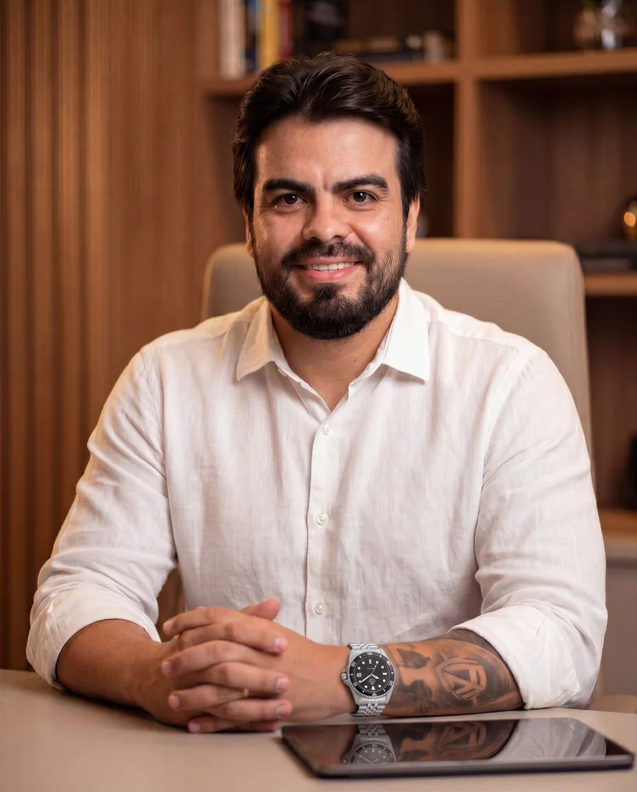 Wallyson Aleixo, de camisa branca, sentado à mesa com as mãos cruzadas